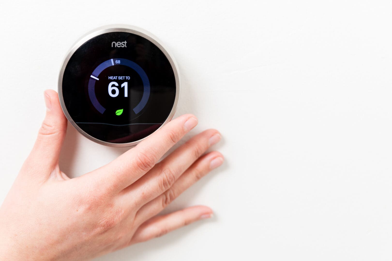 A person is touching the nest thermostat.