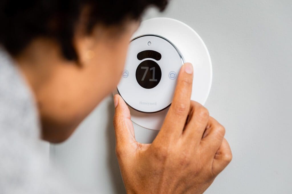 A person adjusting the temperature of an electric heater.