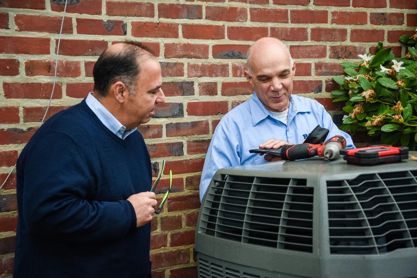 Two men are looking at a air conditioner.