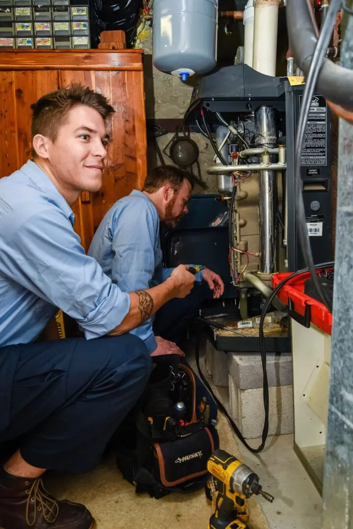 Two men working on a furnace in an old house.